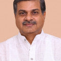 Headshot of a man in a white kurta with a neutral background.
