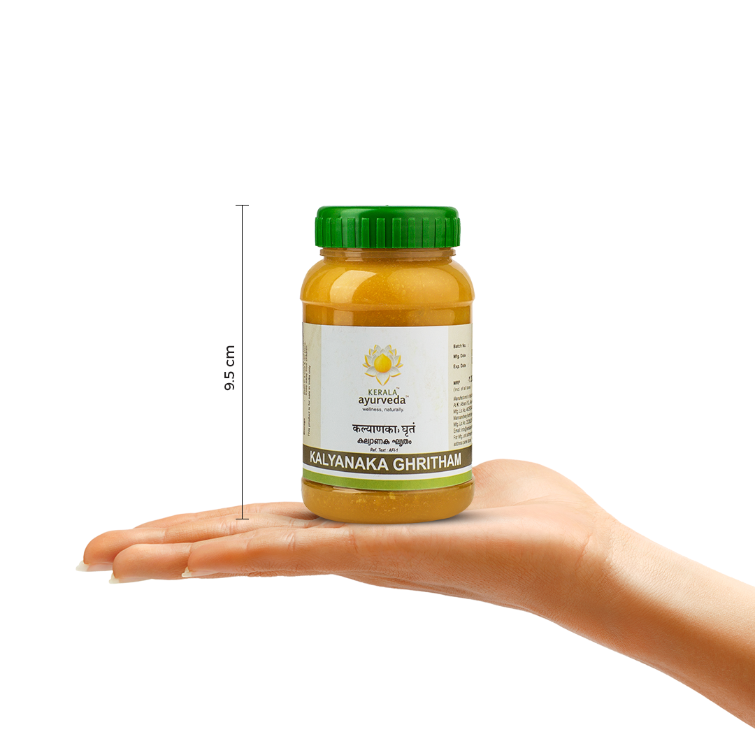 A hand holding a Kalyanaka Ghritham jar, with a measurement indicator showing its height as 9.5 cm. The product name and brand logo are visible on the label. – Kerala Ayurveda India